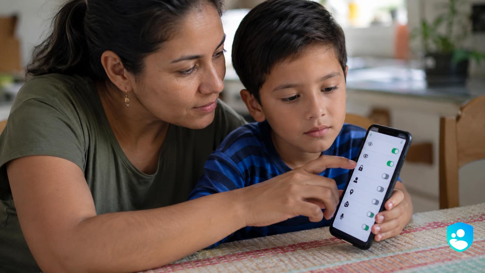 Una madre configura junto a su hijo los ajustes de privacidad de WhatsApp en el celular